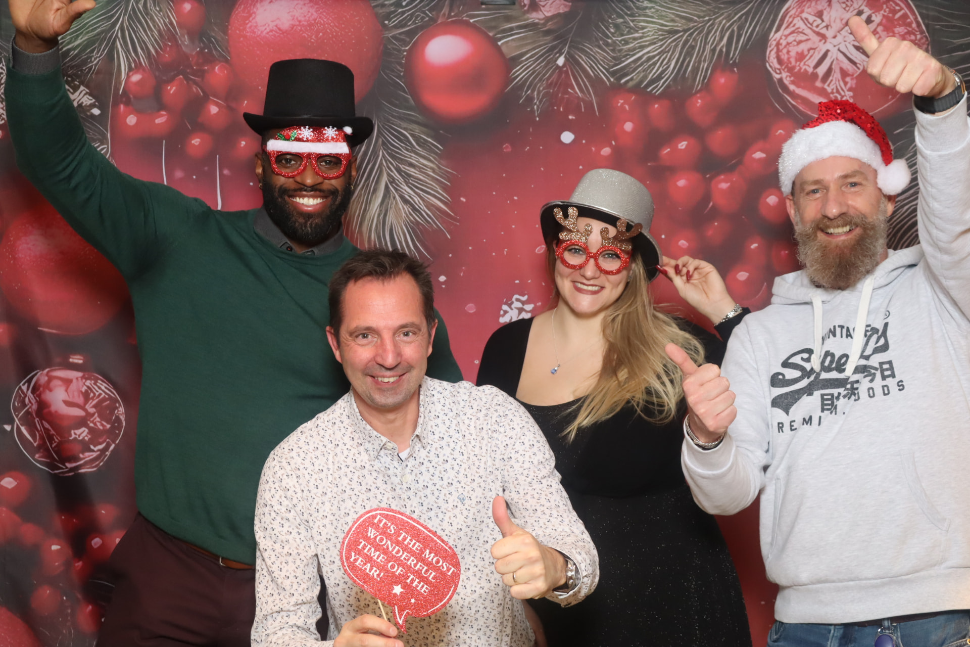 Vier Gäste feiern mit weihnachtlichen Requisiten vor der Fotobox
